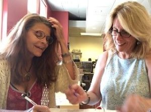 Two teachers sitting at a table smiling and going over documents together.